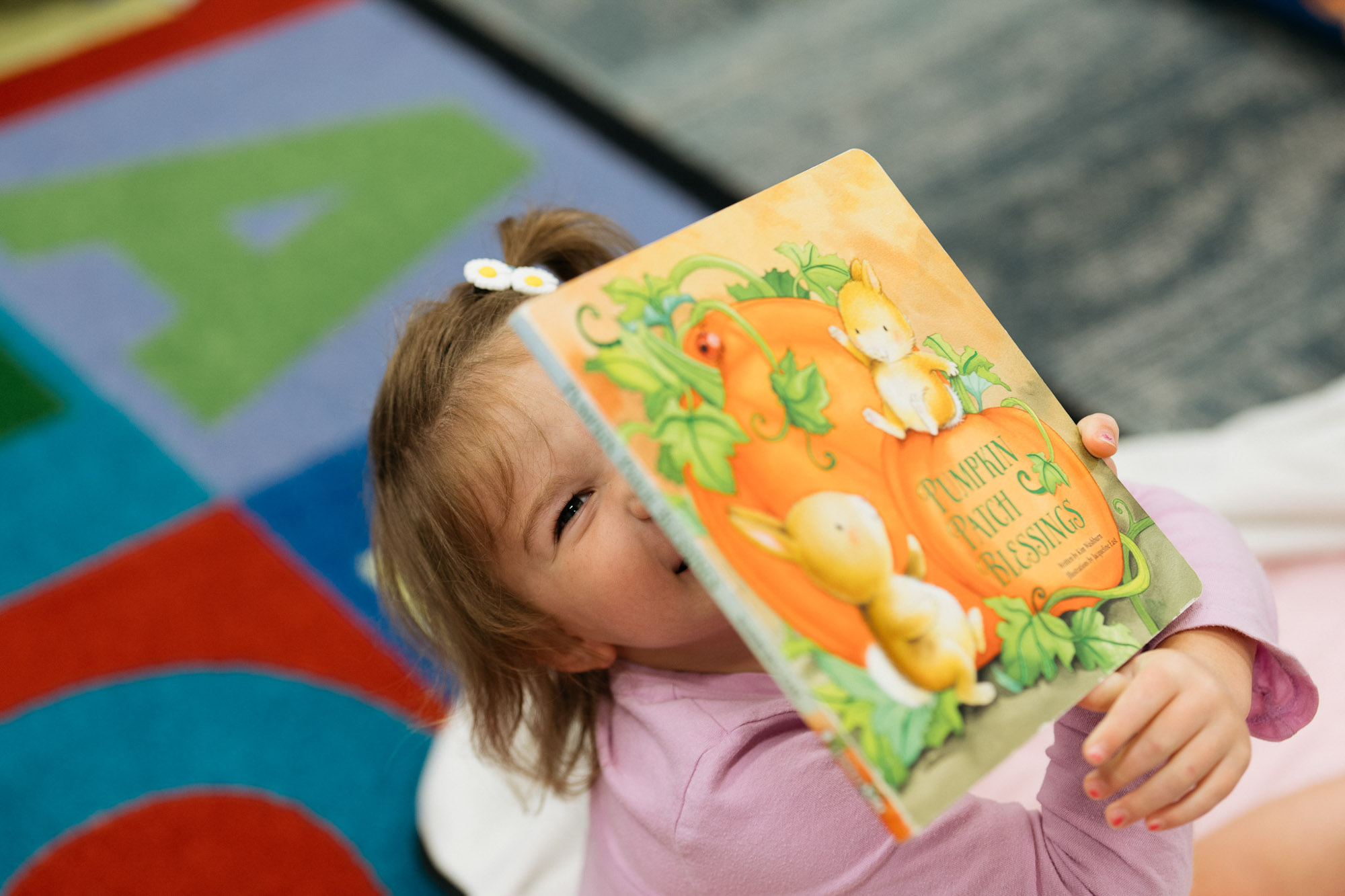 Child holding a book and smiling.